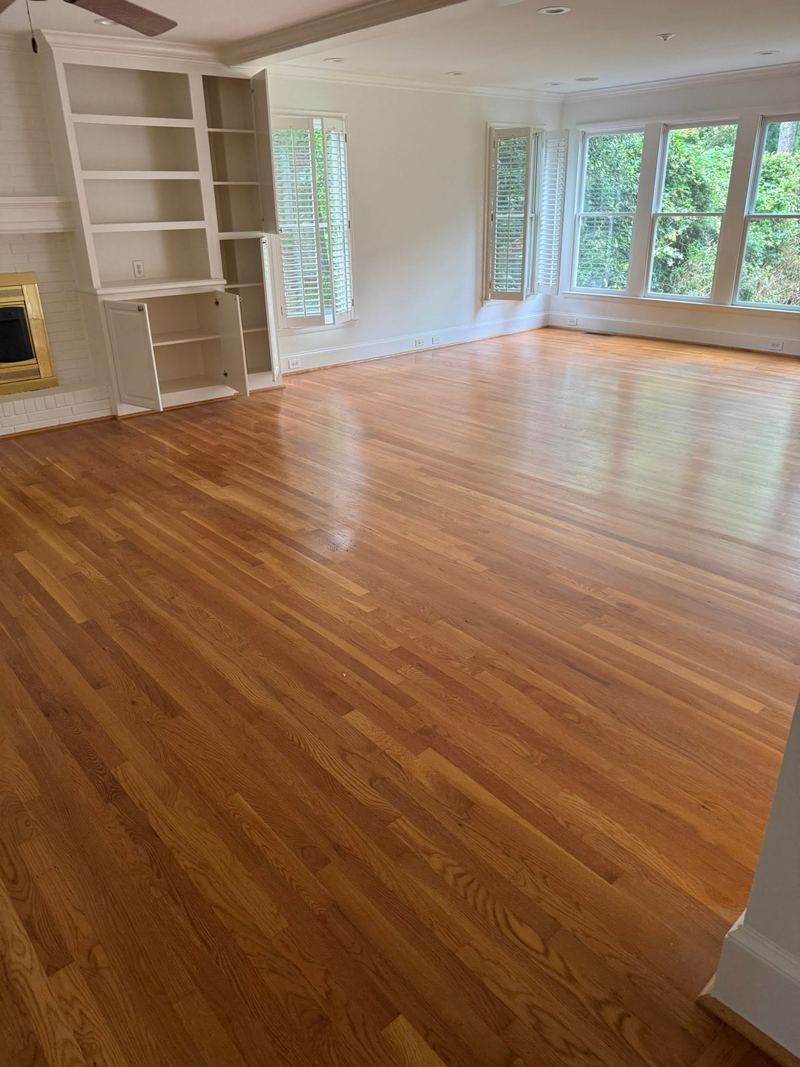 Family room with built-in shelves and a glossy natural red oak floor
