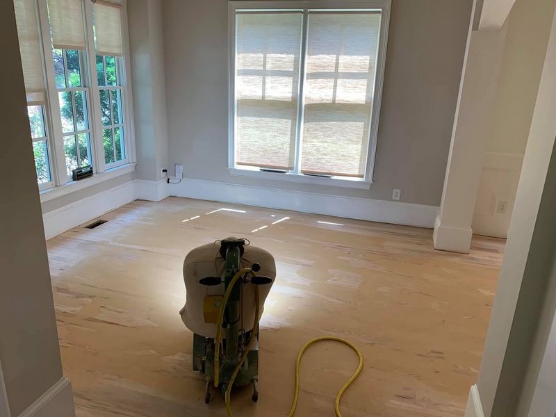 Floor sander in an empty room partway through sanding